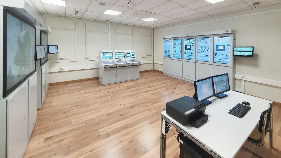 Full-mission engine room simulator with touchscreen consoles and switchboard panels